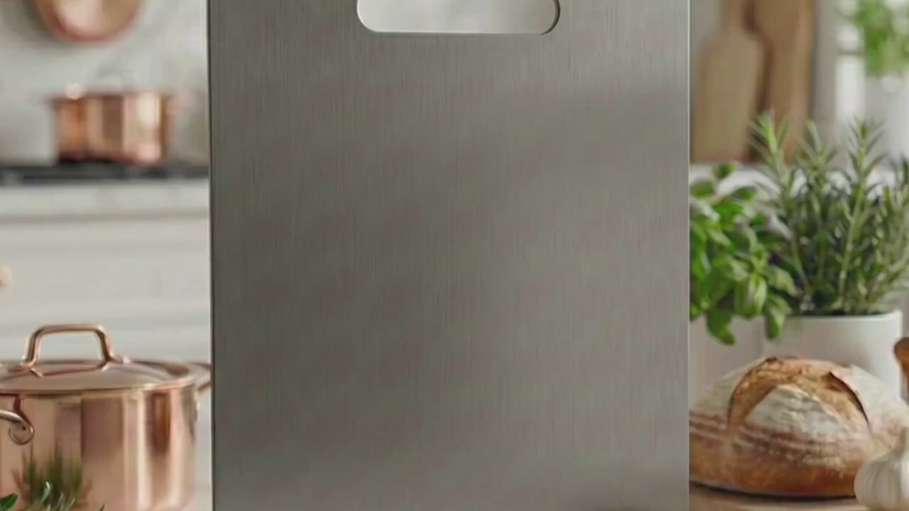 Load video: Close up of a pure titanium chopping board being used to slice fresh juicy fruit. The knife glides smoothly without scratching the surface, demonstrating the durable and scratch-resistant benefits of titanium kitchenware