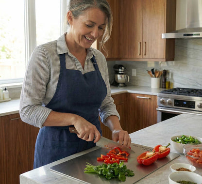 Woman slicing fresh fruit on an antibacterial titanium chopping board by Life Upgrade Co for healthy meal prep.